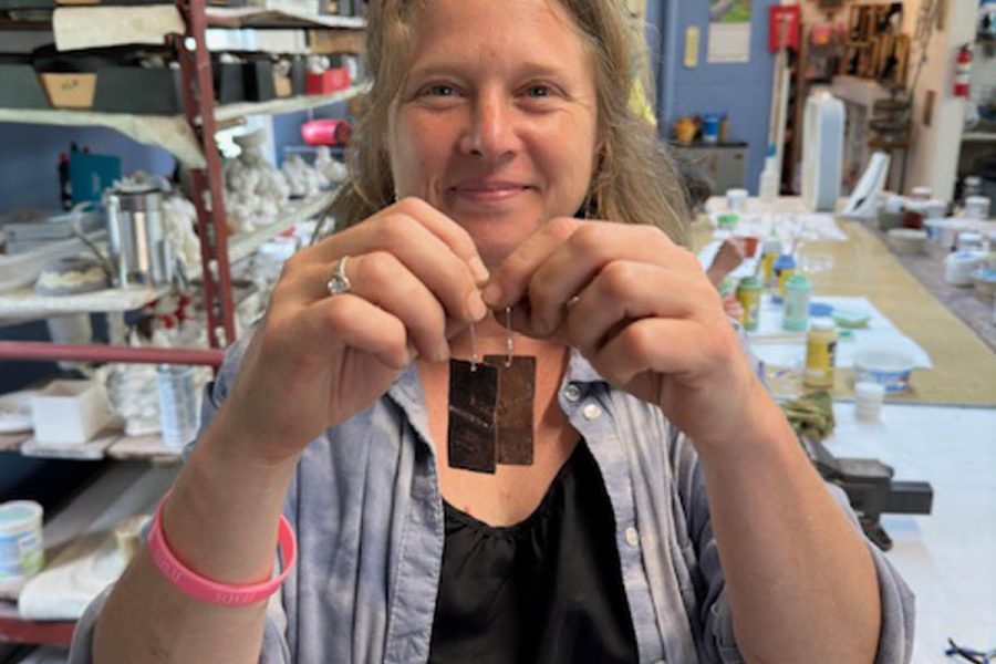 Student holding pair of copper fold-formed earrings created in class at the Somerset Artists' Co-Op in Somerset, Ohio.