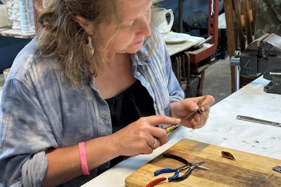 Student creating a pair of copper fold-formed earrings created in class at the Somerset Artists' Co-Op in Somerset, Ohio.