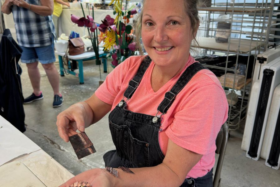 Student holding pair of copper fold-formed earrings created in class at the Somerset Artists' Co-Op in Somerset, Ohio.