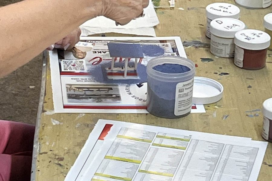 Glass enameling student sifts powdered glass enamel onto copper in preparation for firing in the kiln.