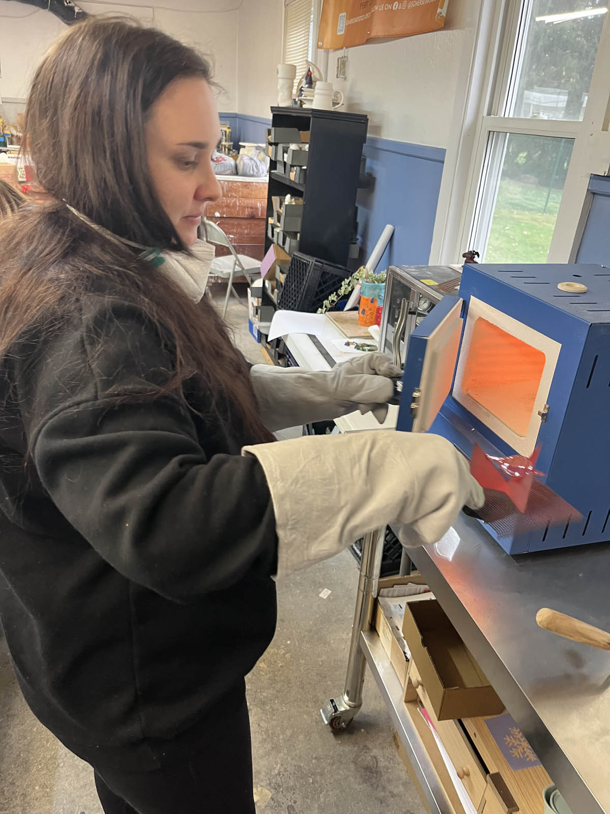 Introduction to Enameling student placing her piece in the enameling kiln at the Somerset Artists' Co-Op