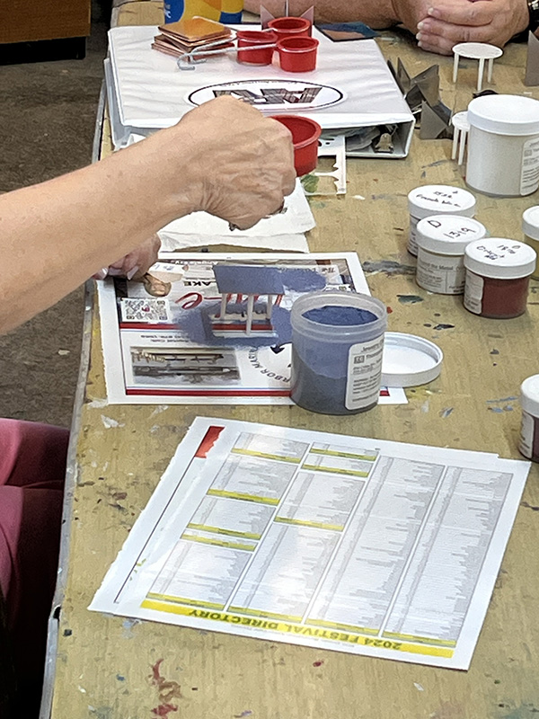 Hand shaking sifter of glass enamel powder onto copper substrate in enamel class at the Somerset Artists' Co-Op.