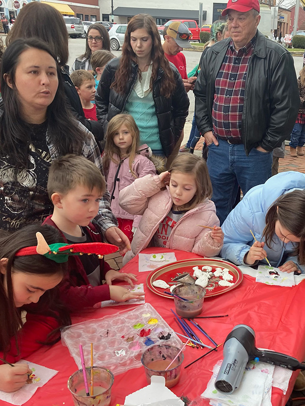 Children gathered at the Somerset Artists' Co-Op table during Small Towne Christmas, painting clay ornaments.